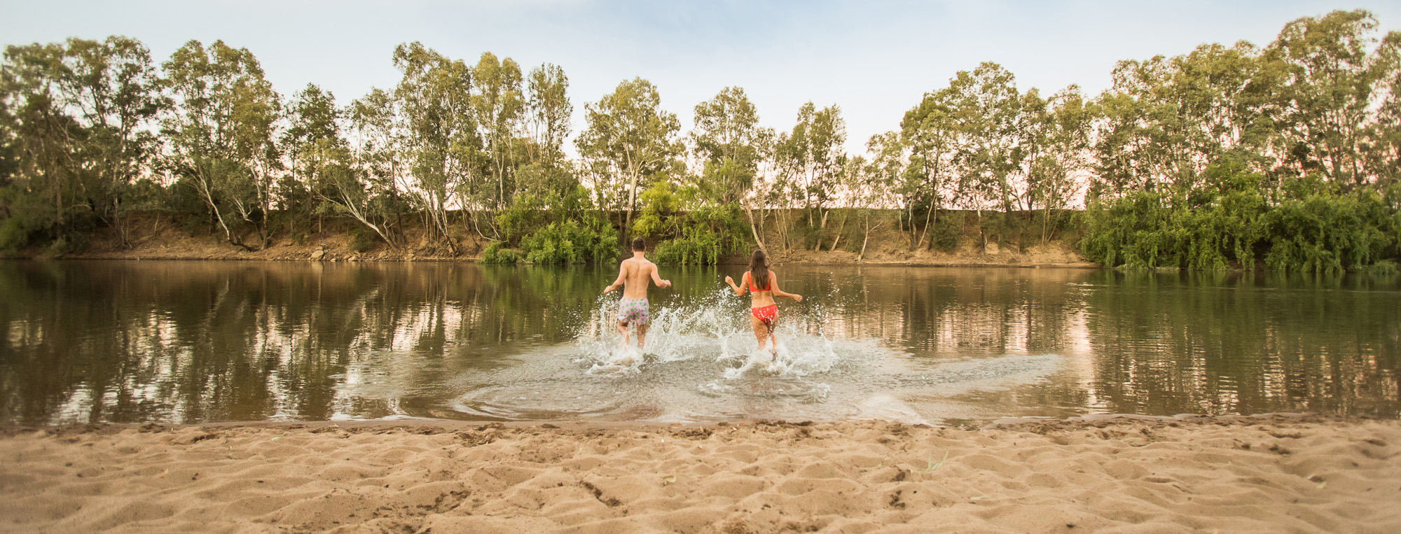 Boy and girl running into the water at Riverside: Wagga Beach