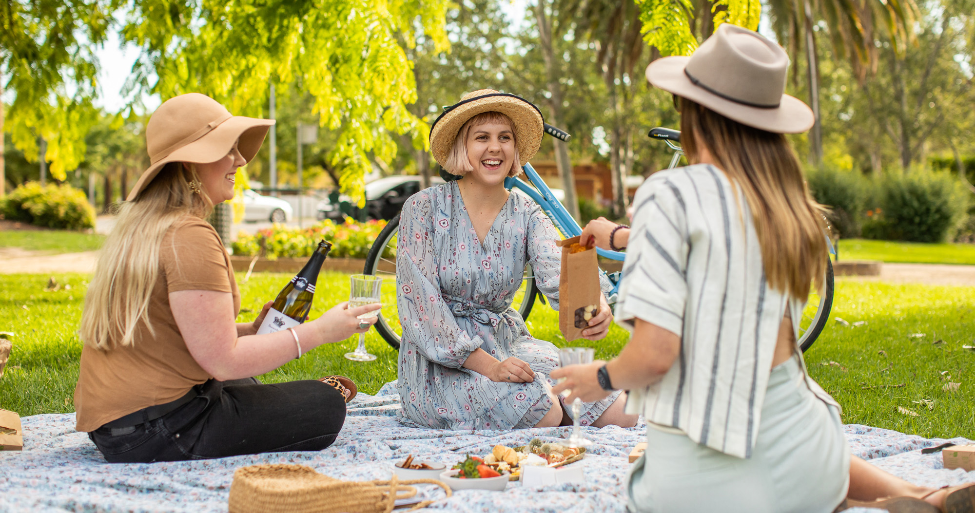 Three female friends enjoying a picnic in Wagga Wagga's Victory Memorial Gardens.