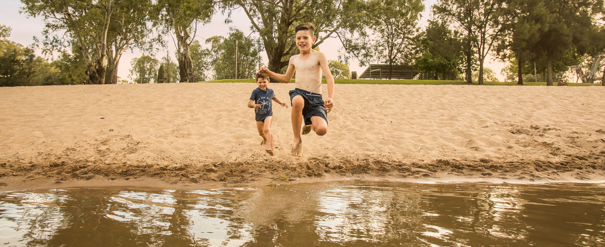Two boys running and jumping into the water at Riverside: Wagga Beach