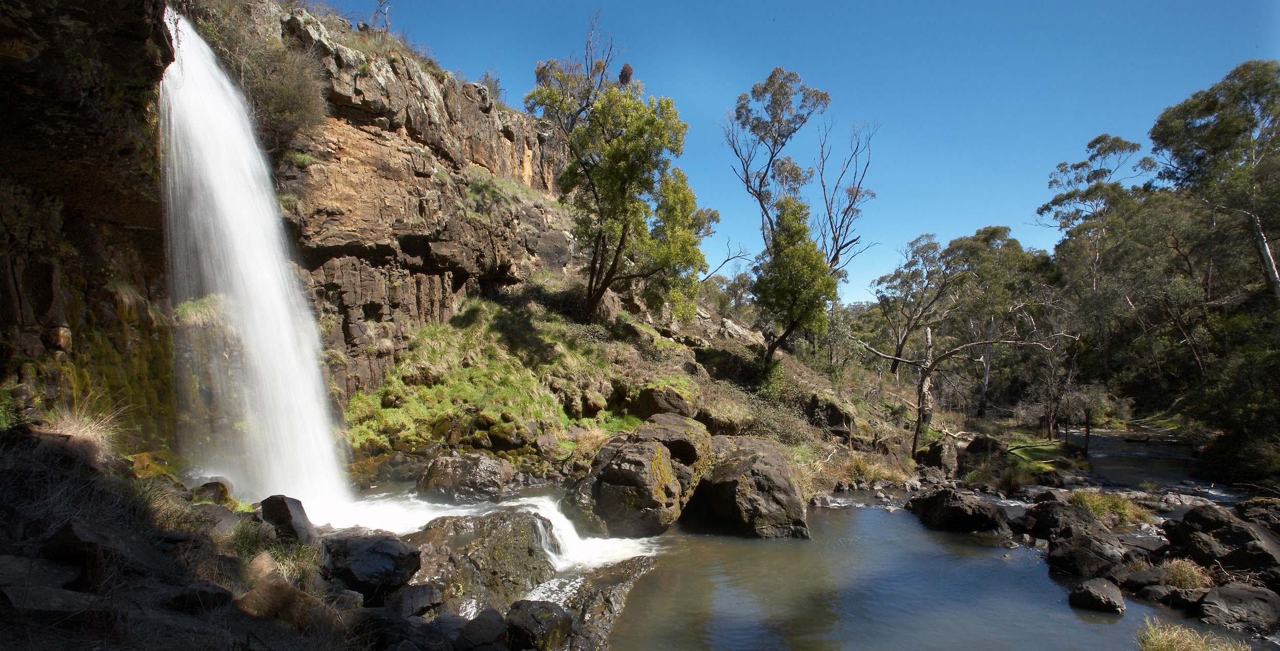 Water gushing over a waterfall into the pool below. 