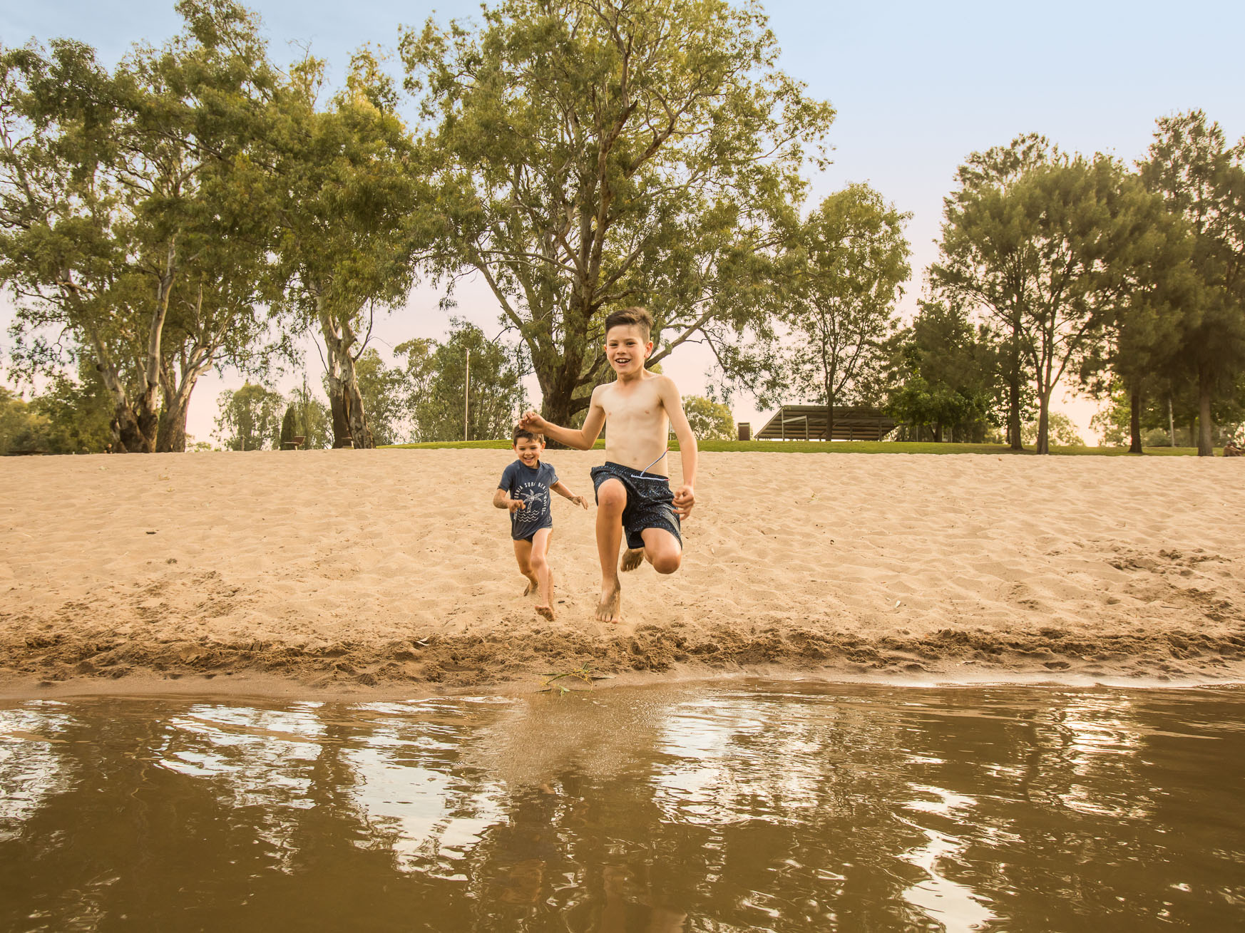Two boys running and jumping into the water at Riverside: Wagga Beach
