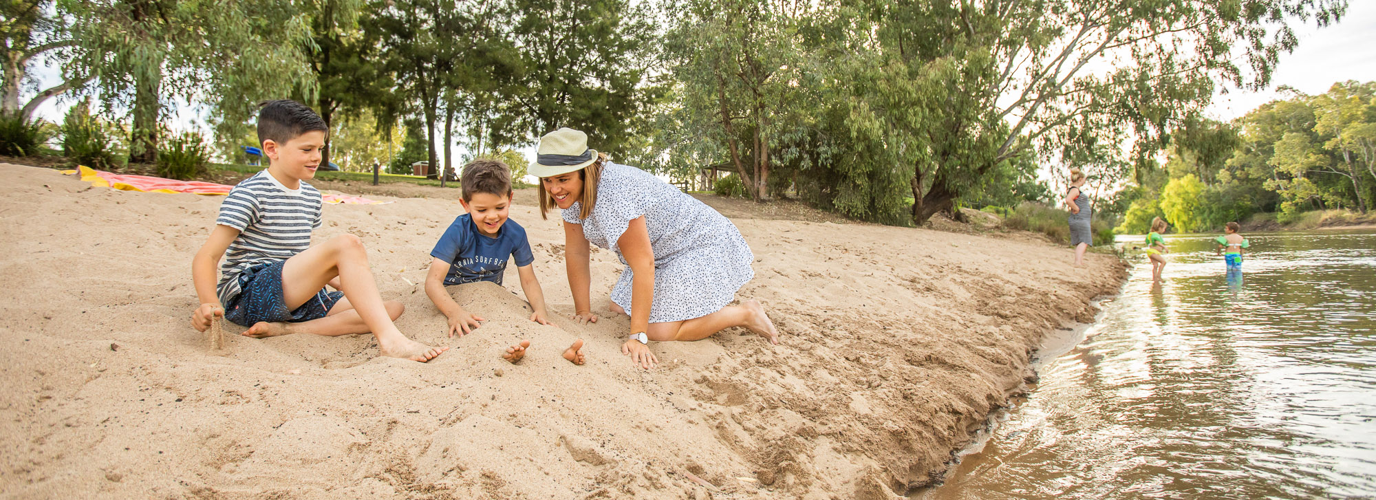 Mother and two sons playing in the sand at Wagga beach 